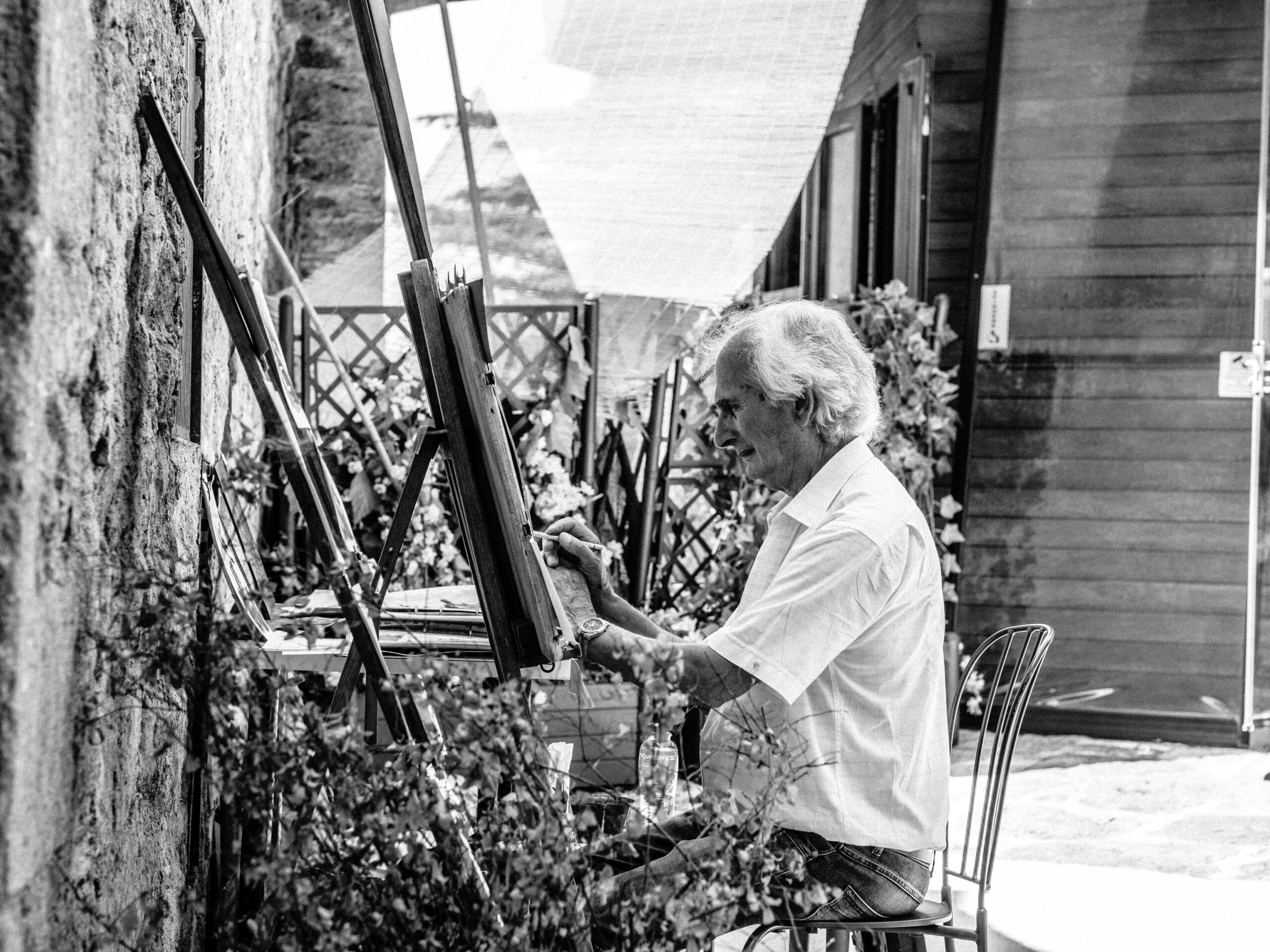 grayscale photo of man sitting while painting